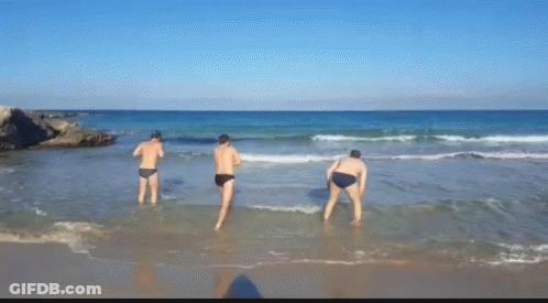 Three Men Are Standing In The Water On A Beach GIF