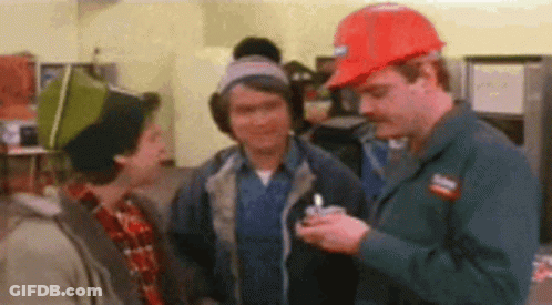 Three Men Are Standing Next To Each Other In A Room . One Of The Men Is Wearing A Hard Hat . GIF