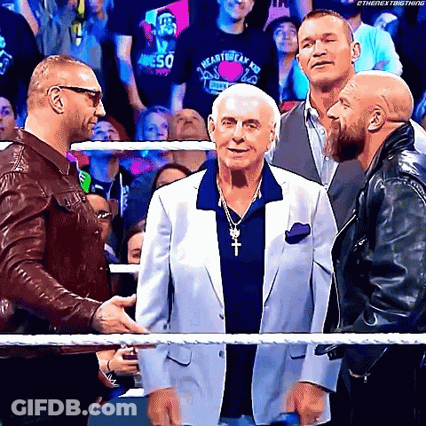 Three Men Are Standing Next To Each Other In A Wrestling Ring Talking To Each Other . GIF