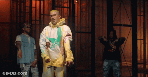 Three Men Are Standing Next To Each Other In Front Of A Building . One Of The Men Is Wearing A Yellow Hoodie . GIF