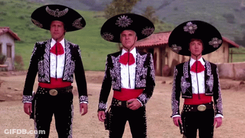 Three Men Dressed As Mariachis Stand In A Dirt Field GIF