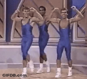 Three Men In Blue Jumpsuits Are Flexing Their Muscles On A Stage GIF
