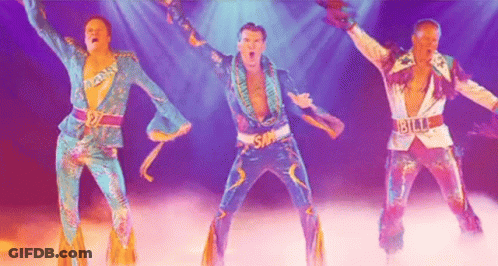 Three Men In Colorful Costumes Are Dancing On A Stage In Front Of A Purple Background . GIF