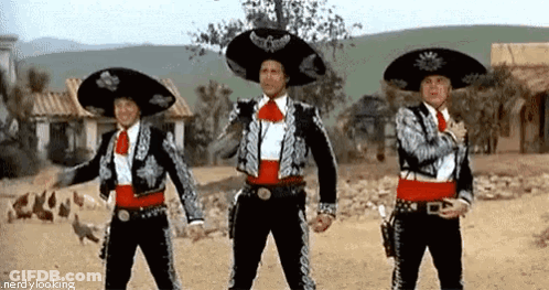 Three Men In Mariachi Costumes Are Standing Next To Each Other In The Desert . GIF
