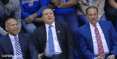 Three Men In Suits And Ties Are Sitting In The Stands At A Basketball Game GIF