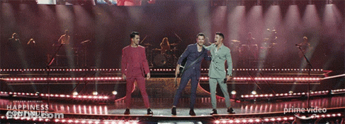 Three Men On A Stage With The Words Happiness Continues On The Bottom Right GIF