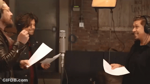 Three Men Singing Into Microphones With No Smoking Sign GIF