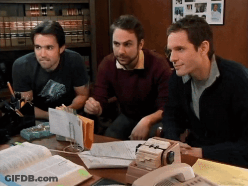 Three Men Sitting At Desk With Papers And Phone GIF