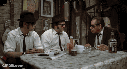 Three Men Sitting At Table With Giant Monster Logo GIF