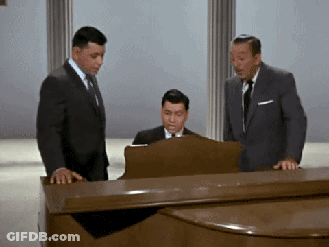 Three Men Standing Around Piano One Playing GIF