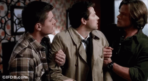 Three Men Standing Together One Holding Arm GIF