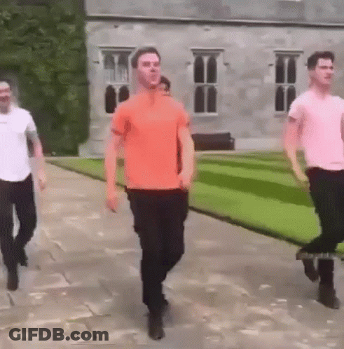 Three Men Walking Past Large Building GIF