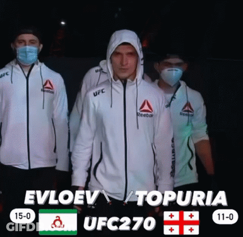 Three Men Wearing Face Masks And Reebok Jackets Are Standing In Front Of A Scoreboard For Ufc 270 GIF