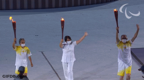 Three People Are Holding Torches In Front Of A Sign That Says ' Paralympic ' GIF