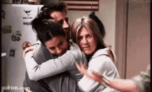 Three People Are Hugging Each Other In A Room . GIF