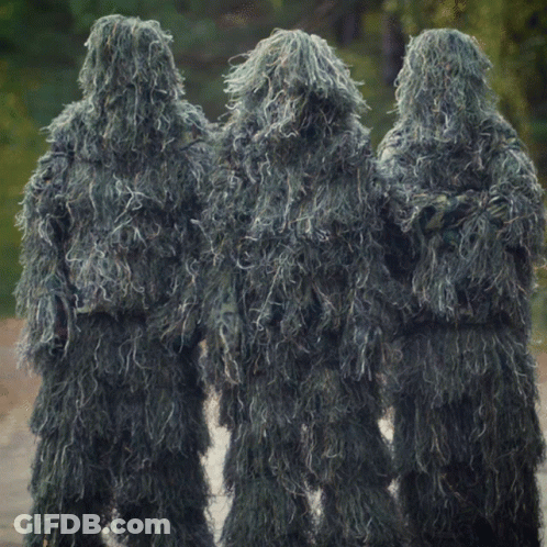 Three People Dressed In Sniper Suits Are Standing In A Line GIF