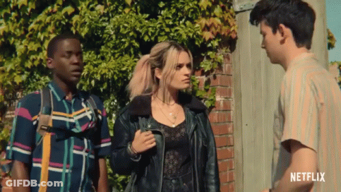 Three People Standing In Front Of A Brick Wall With A Netflix Logo On The Bottom Right GIF
