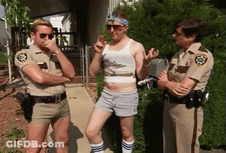 Three Police Officers Are Standing Next To Each Other On A Sidewalk Talking To A Man In Shorts . GIF