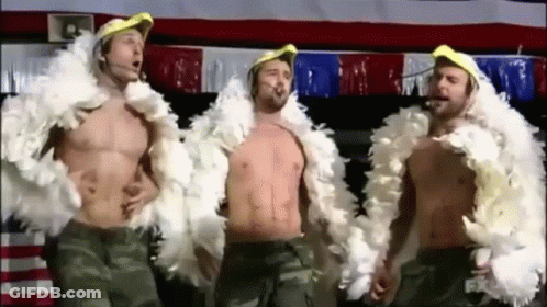 Three Shirtless Men Are Standing Next To Each Other Wearing Feather Boa Jackets . GIF