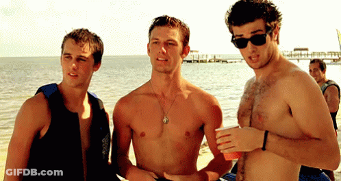 Three Shirtless Men Standing On Beach Talking GIF