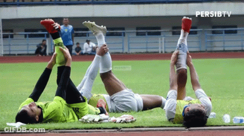 Three Soccer Players Stretch Their Legs On A Field With Persibtv Written In The Corner GIF