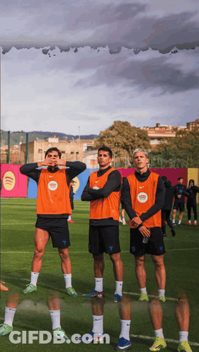 Three Soccer Players Wearing Orange Vests With Spotify Written On Them GIF