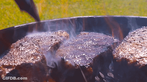 Three Steaks Cooking On A Grill With Smoke GIF