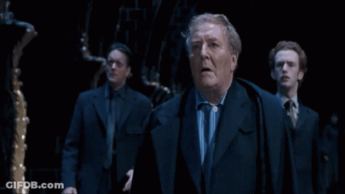 Three Suited Men In Dark Room, One Surprised GIF