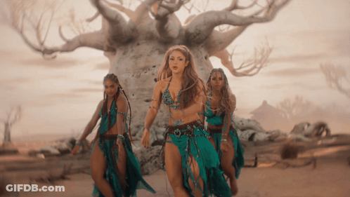 Three Women Are Dancing In Front Of A Tree In A Desert GIF