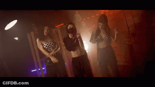 Three Women Are Dancing Together In A Dark Room . GIF