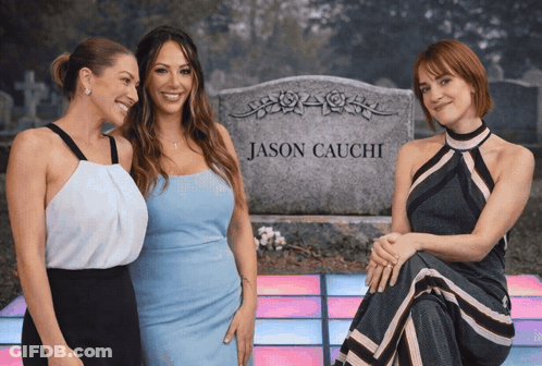 Three Women Are Posing In Front Of A Gravestone For Jason Cauchi GIF