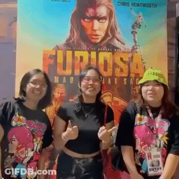 Three Women Are Posing In Front Of A Movie Poster That Says Furiosa GIF