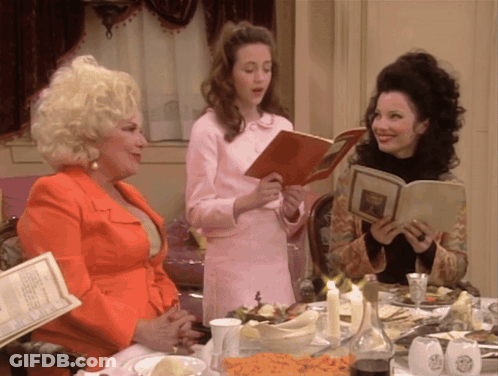 Three Women Are Sitting At A Table Looking At A Menu GIF