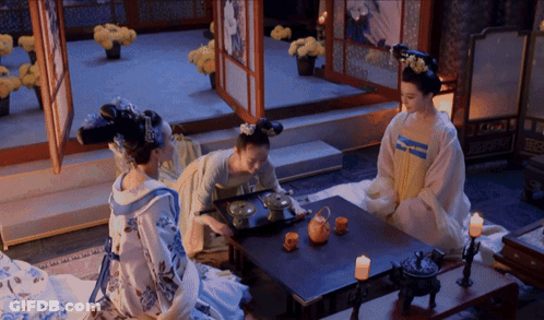 Three Women Are Sitting At A Table With Candles GIF