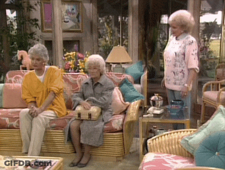Three Women Are Sitting In A Living Room With Wicker Furniture GIF