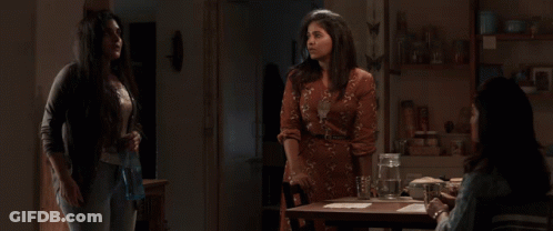 Three Women Are Standing Around A Table With A Pitcher Of Water On It GIF