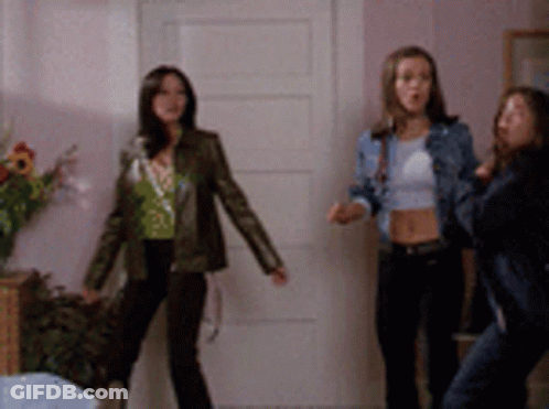Three Women Are Standing In Front Of A White Door GIF