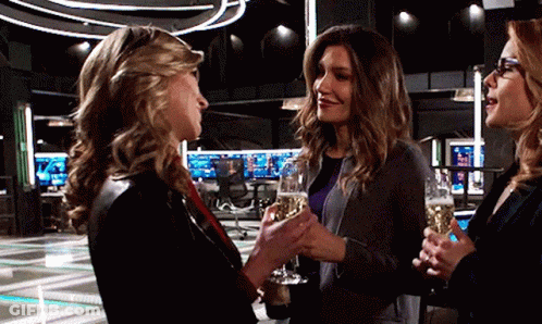 Three Women Are Standing Next To Each Other Holding Champagne Glasses And Talking . GIF