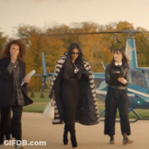Three Women Are Walking Towards A Helicopter With The Letter E On Their Coat GIF