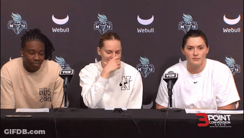 Three Women At Table In Front Of Webull Sign GIF