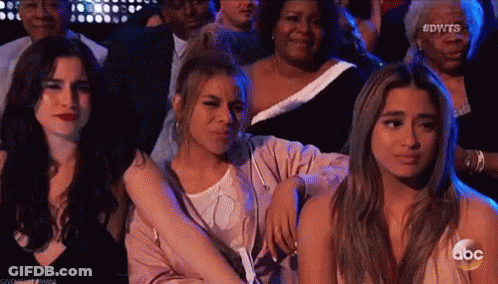 Three Women In Crowd, One Hugging Another GIF