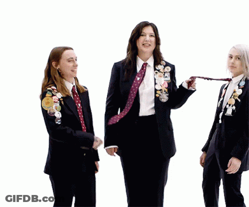 Three Women In Suits And Ties With Pins GIF