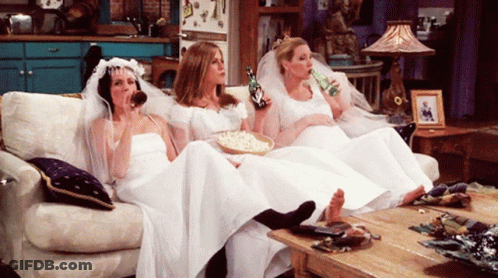 Three Women In Wedding Dresses Sit On A Couch Drinking Beer GIF