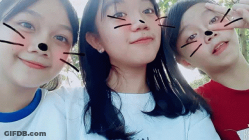 Three Young Girls Are Posing For A Picture Together And One Of Them Has A Cat Face Drawn On Her Face . GIF
