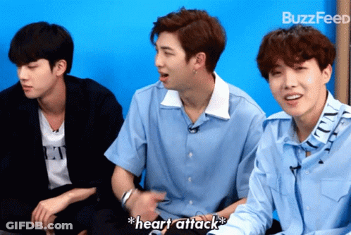 Three Young Men Are Sitting In Front Of A Blue Wall And One Of Them Is Saying " Heart Attack " GIF