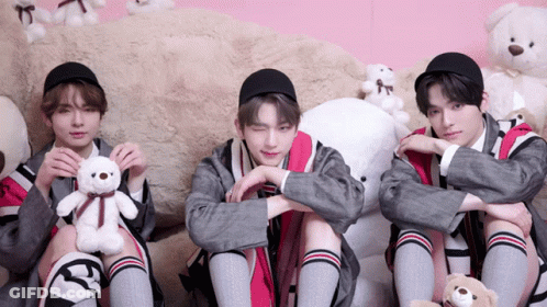 Three Young Men Are Sitting Next To Each Other Holding Stuffed Animals GIF