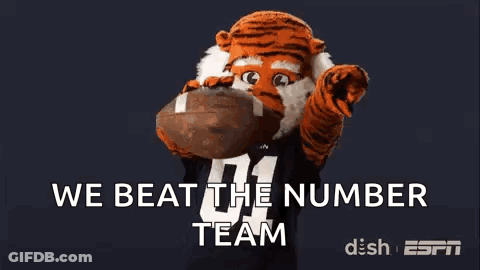 Tiger Mascot Holding Football Saying We Beat The Number Team GIF