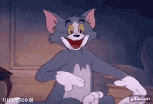Tom From The Cartoon Tom And Jerry Is Laughing While Sitting On A Couch . GIF