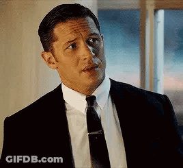 Tom Hardy Is Wearing A Suit And Tie And Looking At The Camera . GIF