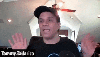 Tommy Tallarico Is Wearing A Black Shirt And A Baseball Cap GIF